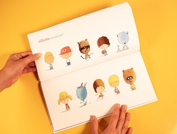 Manos adultas sostienen un libro de cuentos abierto sobre un fondo amarillo liso. Se ven ilustraciones de personajes animados y el texto "¿Quién se lastimó?".