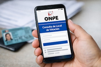 Primer plano de una mano sosteniendo un smartphone con la web de la ONPE para consulta de local de votación. Un DNI peruano borroso en el fondo.
