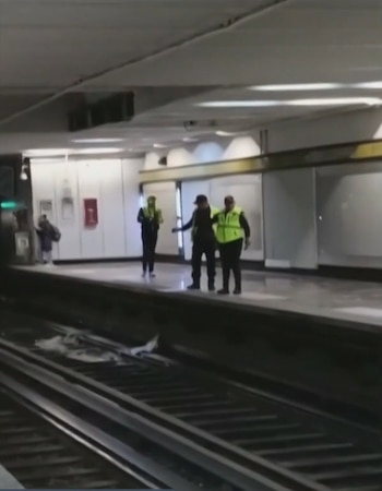 Tres personas con chalecos de seguridad sobre un andén de metro frente a restos de material caídos sobre las vías