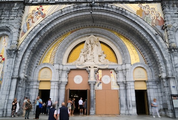 Varias personas entran en la basílica de Nuestra Señora del Rosario en Lourdes, en el suroeste de Francia (AP/Fred Scheiber)