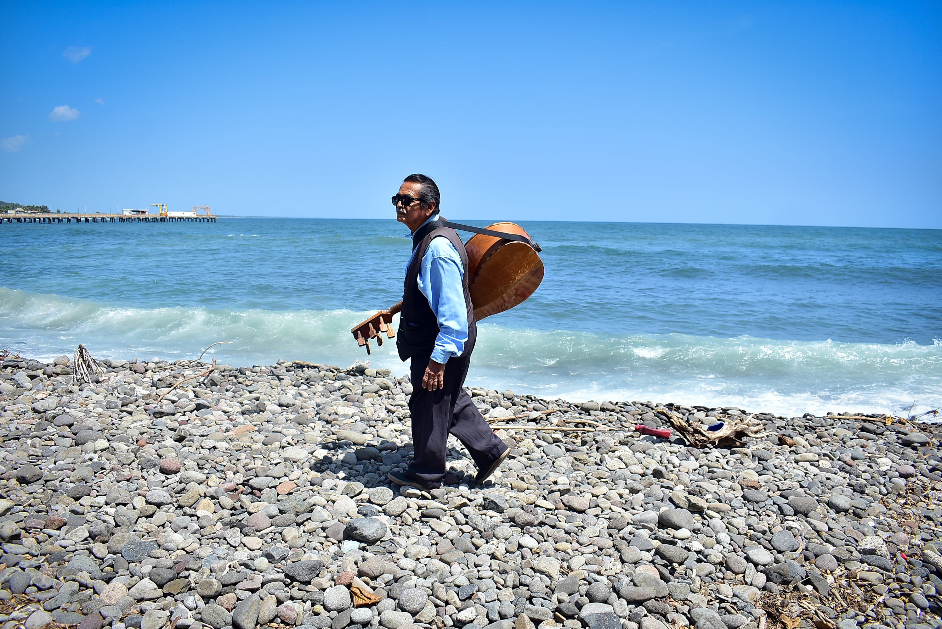 Sobre las rocas del mar, Esteban recorre todos los días los restaurantes de Punta Roca. Ahora, los ingresos económicos en su oficio son complejos, debido a que muchos restaurantes de la zona tienen poca afluencia o, los turistas ya no muestran interés en su talento. (Infobae Centroamérica/Emerson Del Cid)