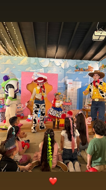 Niños sentados frente a un escenario observan a personas disfrazadas de Buzz Lightyear, Jessie y Woody durante una fiesta infantil