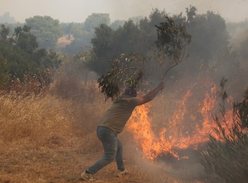 Un voluntario combate las llamas durante un incendio forestal en los alrededores de Mégara, en la región de Ática, Grecia (EFE)