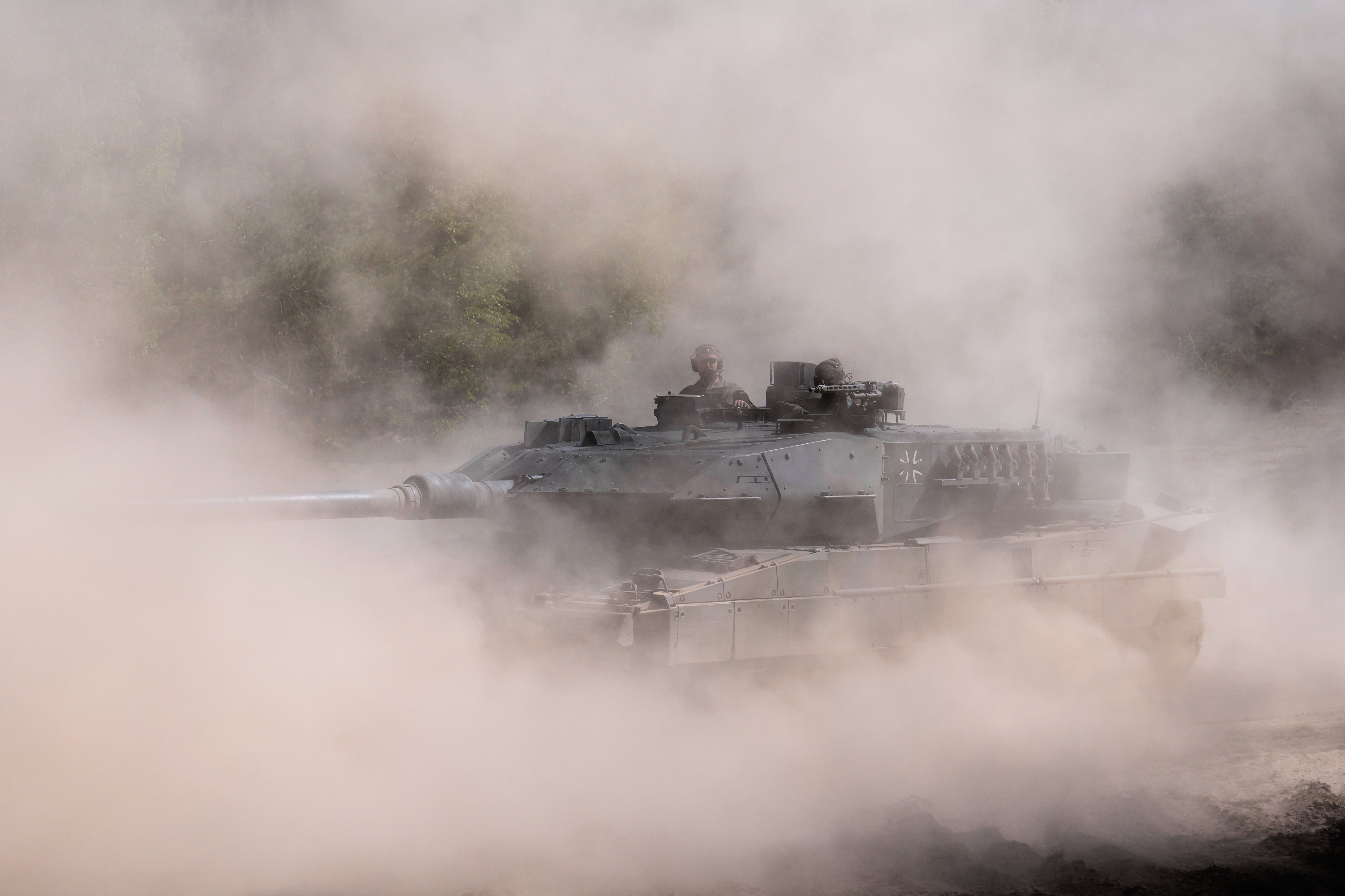 Soldados conducen un tanque Leopard 2 A6 entre el polvo durante la visita del canciller alemán Friedrich Merz al ejército en la base de la Bundeswehr, el jueves 30 de abril de 2026, en Münster, Alemania. (AP Foto/Markus Schreiber)