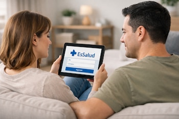 Una mujer y un hombre sentados en un sofá miran una tableta que muestra el logo de EsSalud y un formulario de ingreso con campos para DNI y contraseña.