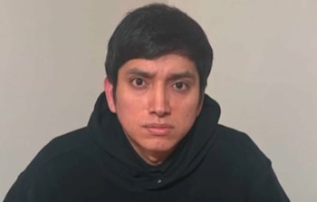 Retrato de frente de un hombre de cabello corto y oscuro, vestido con una sudadera negra con capucha, sobre un fondo neutro