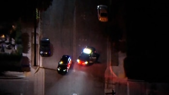 Vista aérea nocturna de una calle con patrullas policiales con luces encendidas y otros automóviles estacionados en la vía