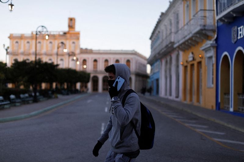 Un hombre con guantes y ropa de frío habla por teléfono mientras camina en Sancti Spiritus, Cuba (REUTERS/Amanda Perobelli/Archivo)