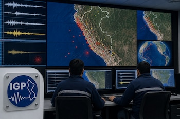 Dos técnicos de espaldas observan pantallas con mapas de Perú y registros de ondas sísmicas, con la placa del logo del IGP en primer plano.