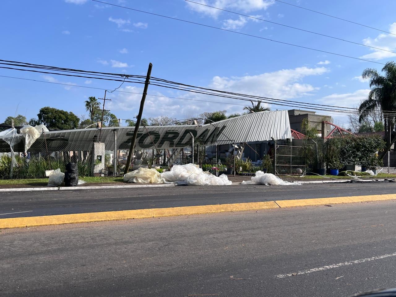 Un local comercial de Concordia presenta su techo metálico y un poste de luz colapsados junto a desechos plásticos esparcidos tras un temporal.