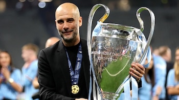 Pep Guardiola sostiene el trofeo de la Liga de Campeones de la UEFA con una medalla de oro en el cuello