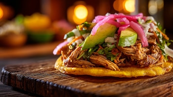 cochinita estilo pibil, recado rojo, naranja agria, maíz nixtamalizado, fritura ligera, platillo festivo, comida ancestral, cocina del sureste mexicano, preparación casera, aroma ahumado, textura crujiente, especialidad regional, gastronomía indígena, receta típica, sabor intenso - (Imagen Ilustrativa Infobae)