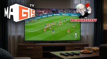 Una smart TV en un mueble de madera muestra un partido de fútbol, con los logos "MAGIS TV" y "ROJADIRECTATV" y un árbitro caricatura. En primer plano hay mandos y bocadillos.