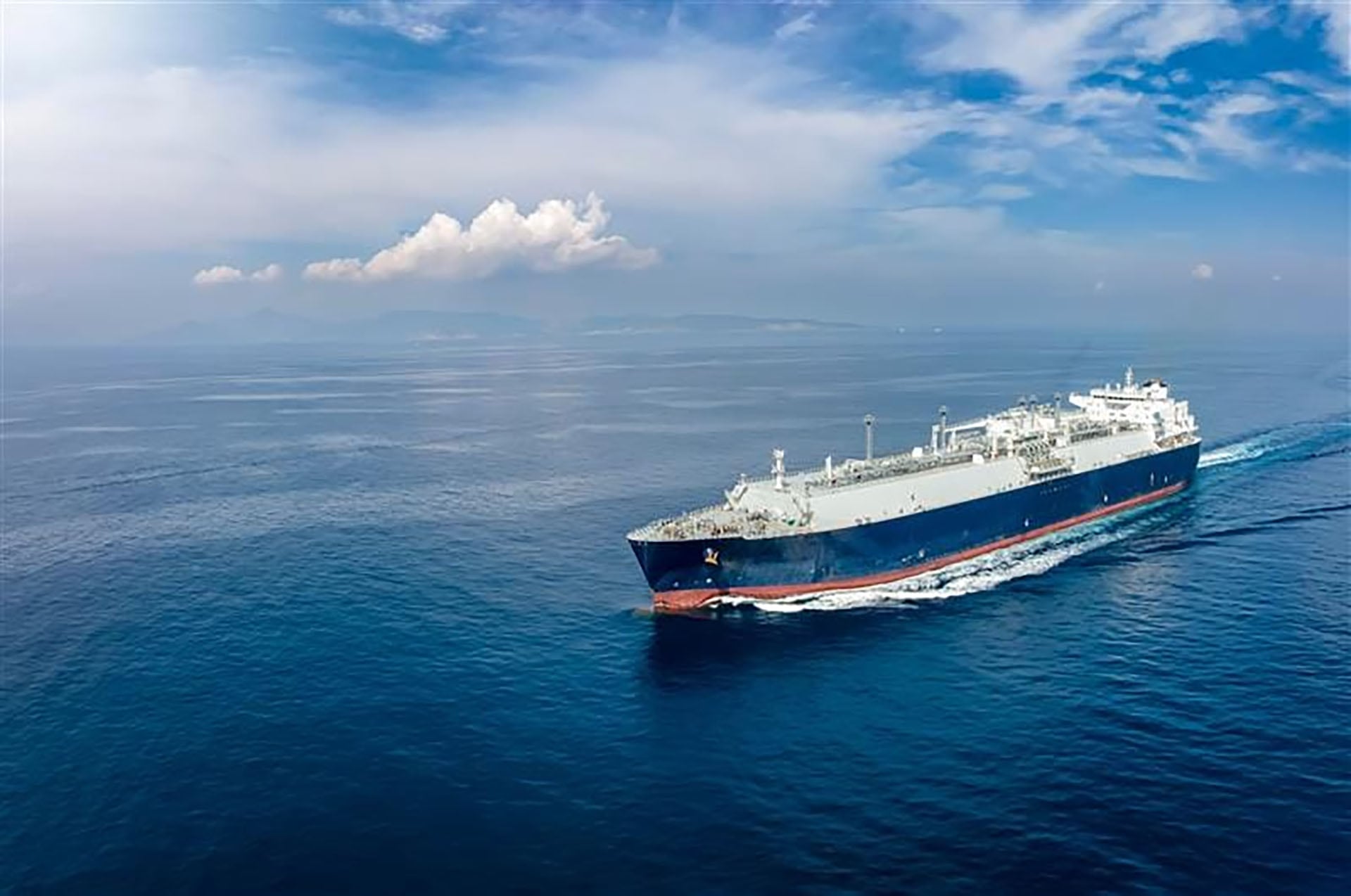 Un buque transportador de gas natural licuado, vinculado a la operación YPF Argentina LNG, navega en aguas abiertas bajo un cielo parcialmente nublado.