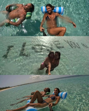 Diego Torres y Martina Díaz Radonic, recostados sobre colchonetas inflables en aguas cristalinas del Caribe. En el fondo arenoso, una inscripción formada con piedras que reza "I Love you"
