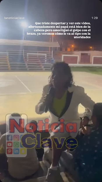 Cantante de pelo rizado y chaqueta blanca con solapas negras, actuando con micrófono en un escenario exterior por la noche. Luces y público parcial visible