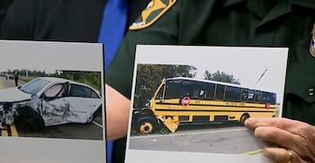 Unas manos uniformadas sostienen dos fotos impresas de un auto blanco dañado y un autobús escolar amarillo accidentado