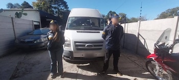 Dos agentes de la PFA, un hombre y una mujer, de pie frente a una furgoneta Ford Transit blanca. Un coche gris y una motocicleta roja son parcialmente visibles