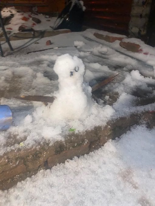 Una pequeña figura elaborada con graupel permanece sobre un murete de ladrillo cubierto de hielo tras el paso de una tormenta invernal.