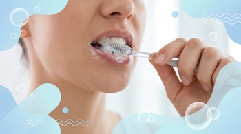 Primer plano de la boca de una persona mientras se cepilla los dientes con un cepillo manual y espuma blanca.