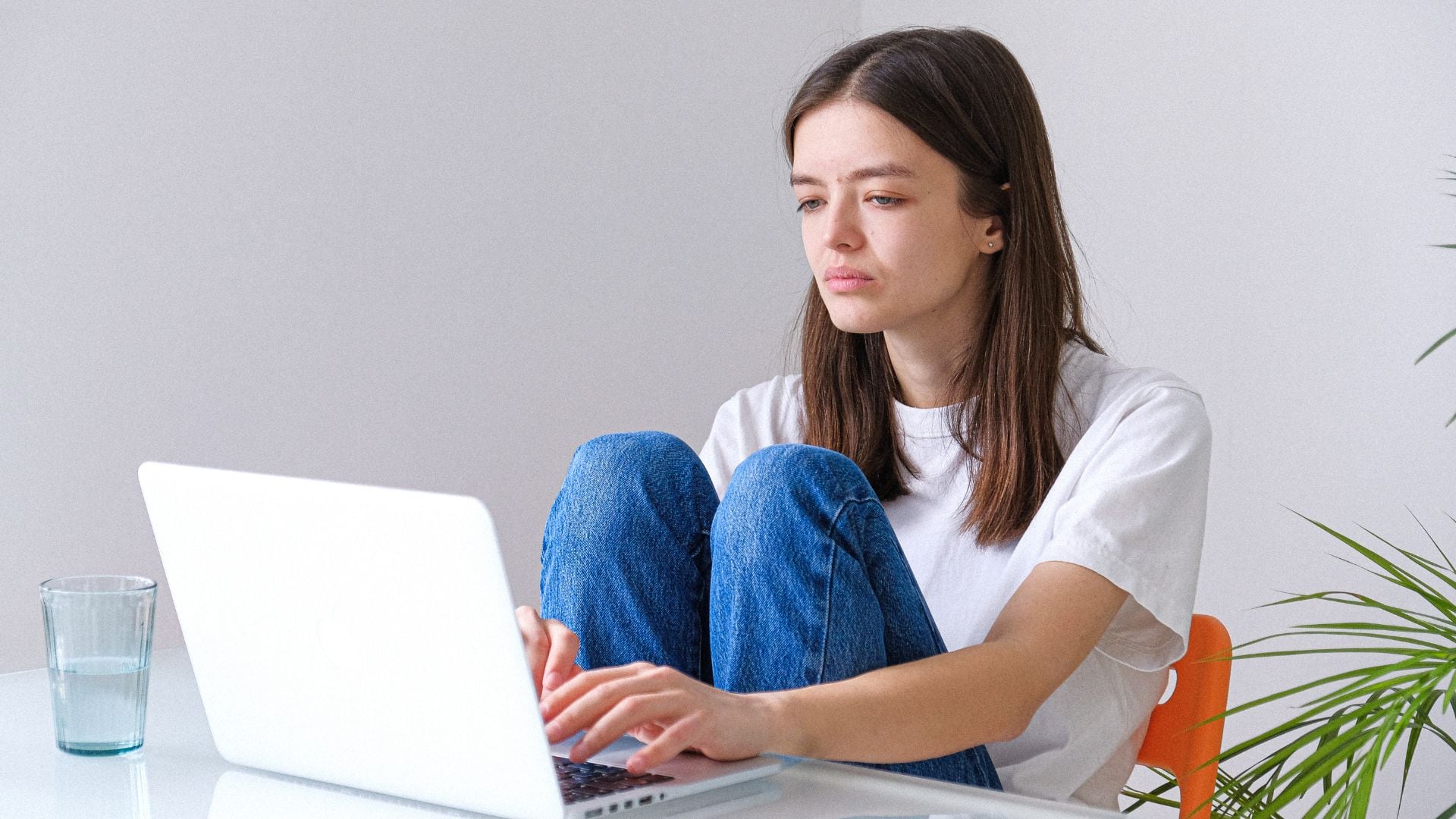 Una chica triste escribe en su ordenador (Canva)