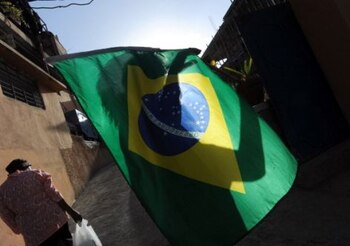 A Haitian woman holds a Brazilian flag while celebrating the triumph of Brazil vs Colombia during quarterfinal match in the World Cup Brazil 2014, in Port-au-Prince, on July 4, 2014. Brazil beat Colombia 2-1 to secure World Cup semi-final place. AFP PHOTO/Hector RETAMAL (Photo credit should read HECTOR RETAMAL/AFP/Getty Images)