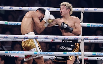 Dos luchadores en un ring: uno de cabello rubio con guantes negros golpea al otro de cabello oscuro que protege su rostro con guantes blancos y oro