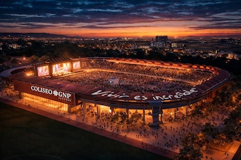 Vista aérea del 3 De Marzo Stadium repleto durante un concierto al anochecer, con grandes pantallas de video, y un cielo naranja y azul oscuro