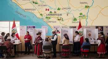 Varias personas votan en un centro electoral, con cabinas de votación y la bandera de Perú. Detrás, un gran mapa de la región de Lambayeque.