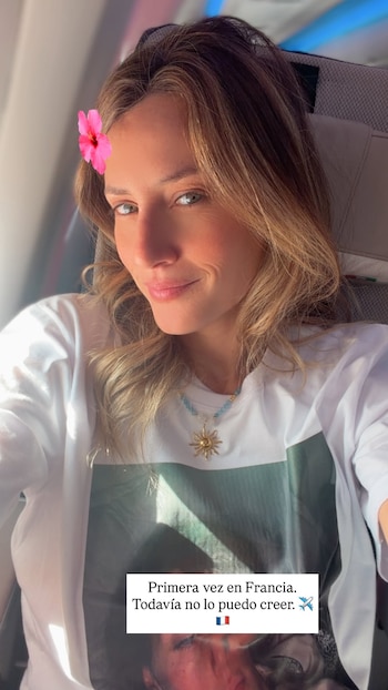 Mujer rubia en sudadera blanca abraza a niño pequeño de camiseta oscura, frentes unidas. Fondo con pared de madera y pared clara. Maleta y texto visible