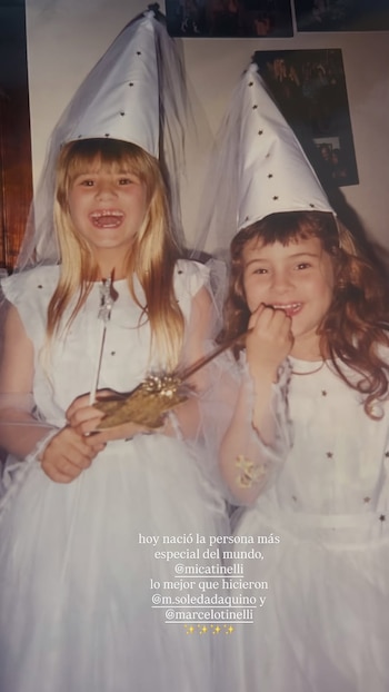 Dos niñas disfrazadas con vestidos y sombreros cónicos blancos posan sonrientes mientras sostienen varitas mágicas en una fotografía antigua