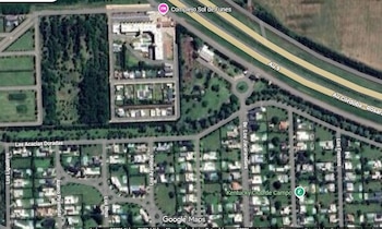 Imagen satelital de un paisaje urbano con una autopista principal, intersecciones viales, complejos residenciales, edificios y extensas zonas verdes