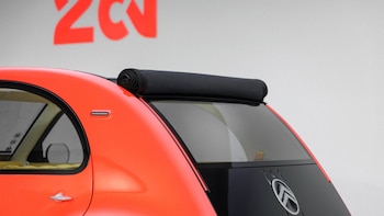 Parte trasera de un vehículo naranja con techo de lona negra enrollado y el emblema de Citroën en la parte posterior
