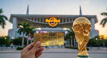 Una mano sostiene una entrada dorada de fútbol frente a una Copa Mundial dorada con bordes blancos. Al fondo, el Hard Rock Stadium de Miami al atardecer con palmeras.