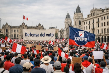 Gran multitud marchando en una calle de Lima, portando banderas peruanas y un banner blanco con 'Defensa del voto'. Edificios históricos y bandera de ONPE visibles.