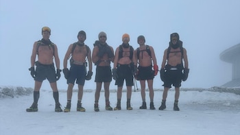 Primer plano de un hombre con barba, André Schurrle, usando una linterna frontal que ilumina su rostro sobre un fondo oscuro, lleva una camiseta roja