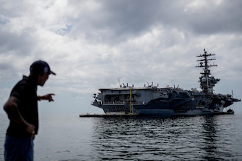 Un trabajador señala el portaaviones de la Armada estadounidense USS Nimitz atracando en el Golfo de Panamá, el lunes 30 de marzo de 2026 (Foto AP/Matias Delacroix)