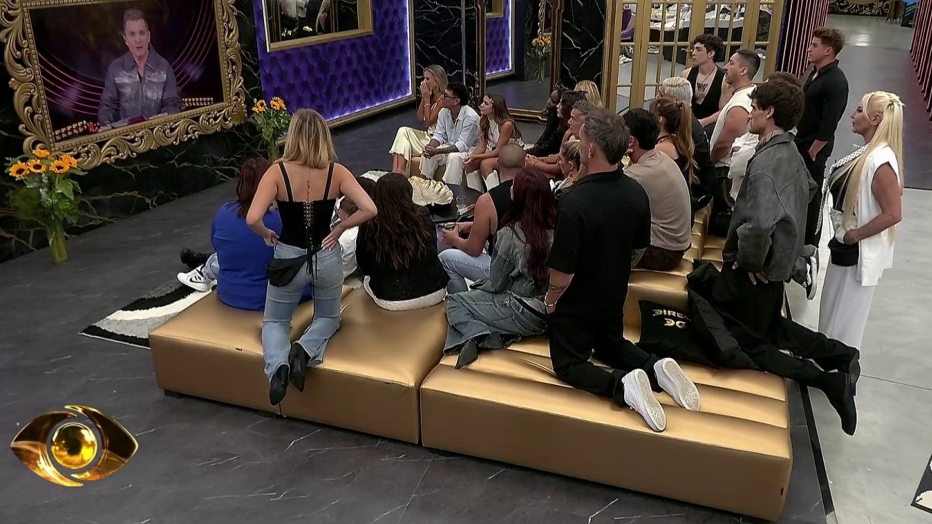 Los participantes de Gran Hermano se congregan en el salón para observar atentamente un mensaje proyectado en pantalla, generando un momento de alta tensión en el programa de Telefe