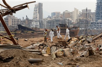 Miembros del equipo forense caminan cerca de los escombros en el lugar de la explosión del martes pasado, en la zona portuaria de Beirut, Líbano, 7 de agosto de 2020 (Reuters)