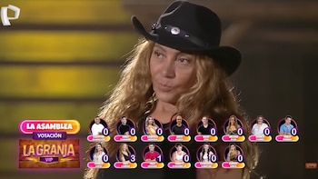 Una mujer de cabello largo y rizado con un sombrero de vaquero oscuro mirando a la izquierda, con una pantalla de votación de reality show debajo