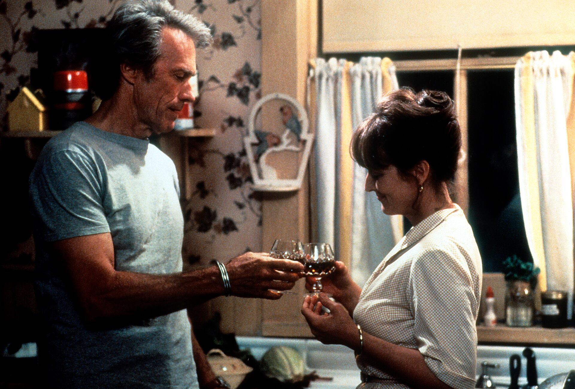 Clint Eastwood and Meryl Streep standing in the kitchen having a cheer in a scene from the film