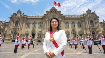 Keiko Fujimori con traje blanco y banda presidencial roja y blanca, frente al Palacio de Gobierno de Perú, con guardias en uniforme.