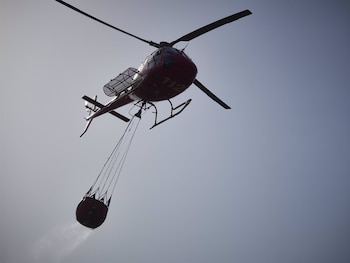 Un helicóptero lanza agua para sofocar un incendio. (Eduardo Sanz - Europa Press)