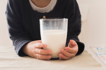 Un niño sostiene en sus manos un vaso de leche (Freepik)