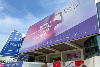 Gran cartel del 'World A.I. Film Festival' con una silueta de mujer en la fachada de un edificio. Un cartel azul de 'Office de Tourisme' es visible a la izquierda