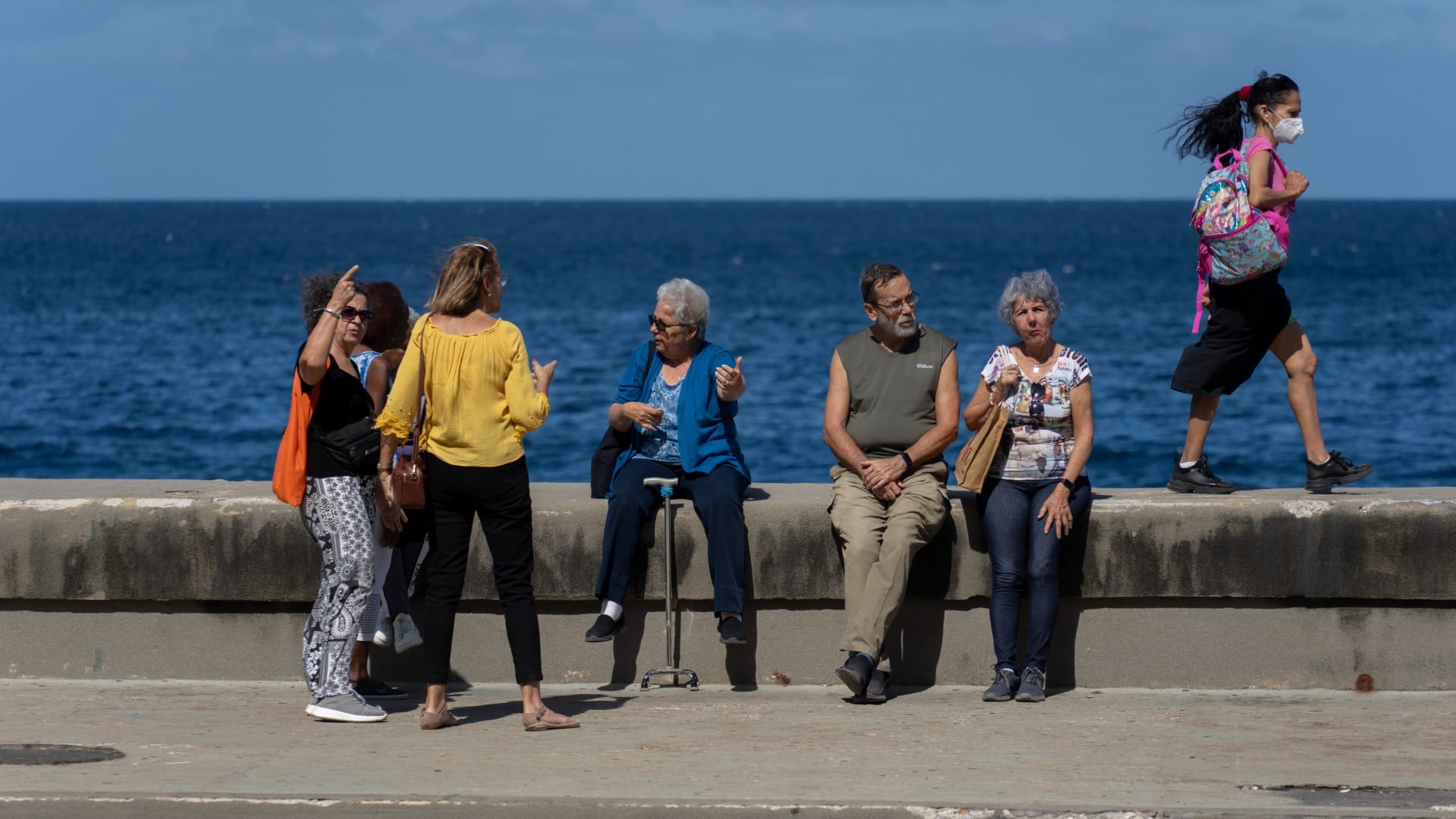 Maylo Pajón Lorenzo, en el centro, habla con amigos después de una clase de baile, mientras está sentada en el malecón de La Habana, el martes 4 de febrero de 2025. (Foto AP/Ramón Espinosa)