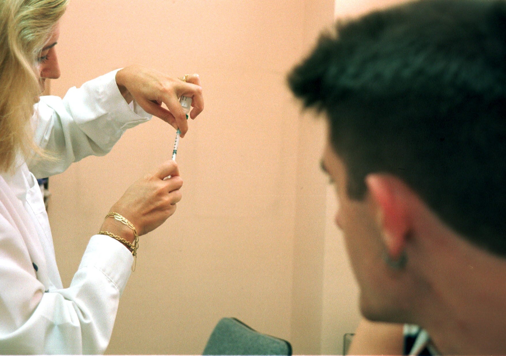 En la imagen de archivo, un joven observa cómo preparan la vacuna contra la meningitis, en un ambulatorio de España. Efe/David Aguilar.