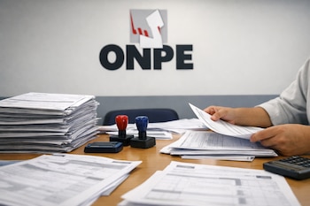 Manos revisando actas electorales en una mesa de madera con sellos y calculadora. Al fondo, el logo negro de la ONPE con su símbolo.