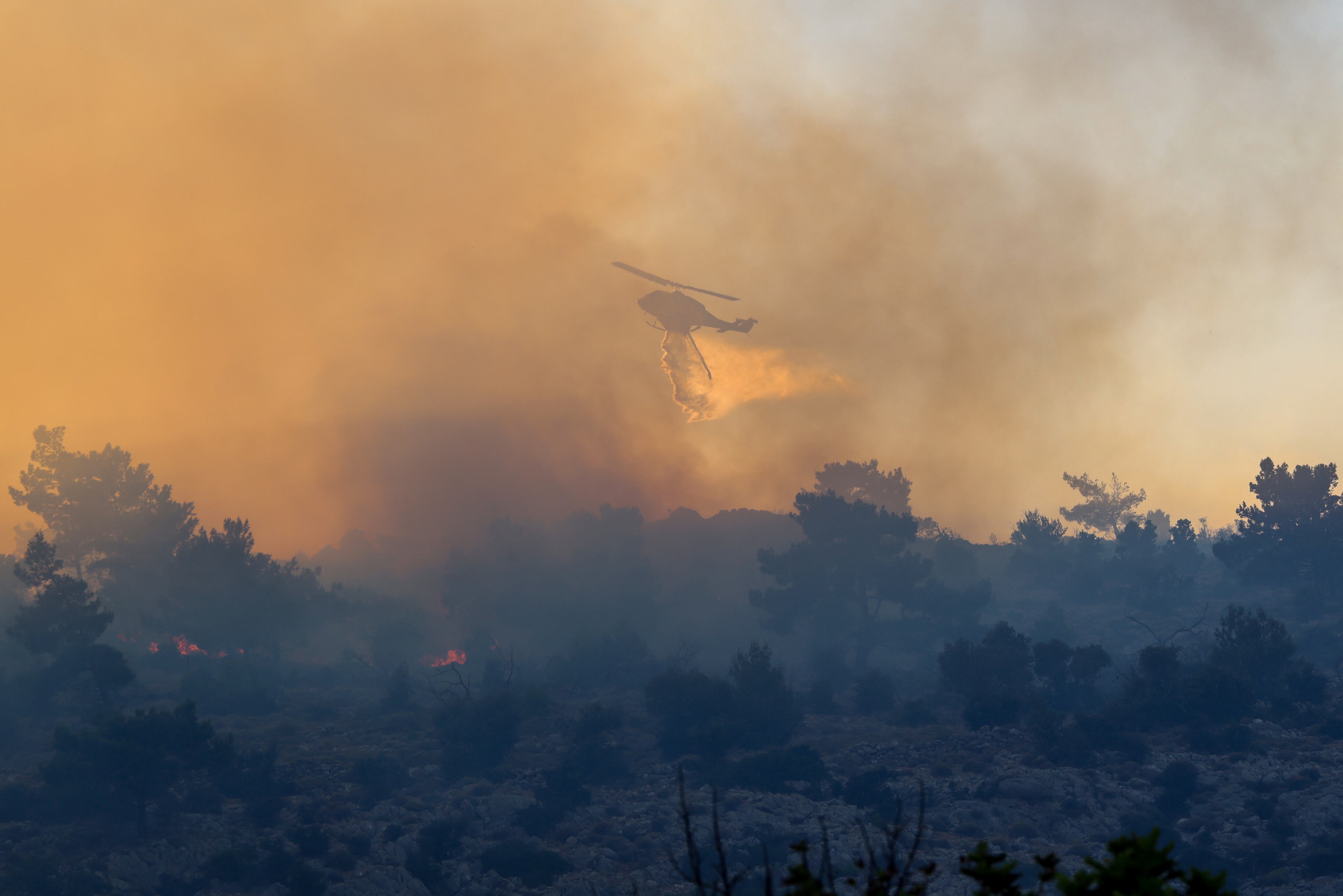 Un helicóptero de bomberos deja caer agua para extinguir el fuego en la zona de Kontylopos, en la isla de Quíos, Grecia, 24 de junio de 2025. REUTERS/Kostas Anagnostou