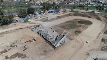 Vista aérea de excavadoras sobre una estructura parcial de hormigón en un circuito de carreras rodeado por caminos de tierra